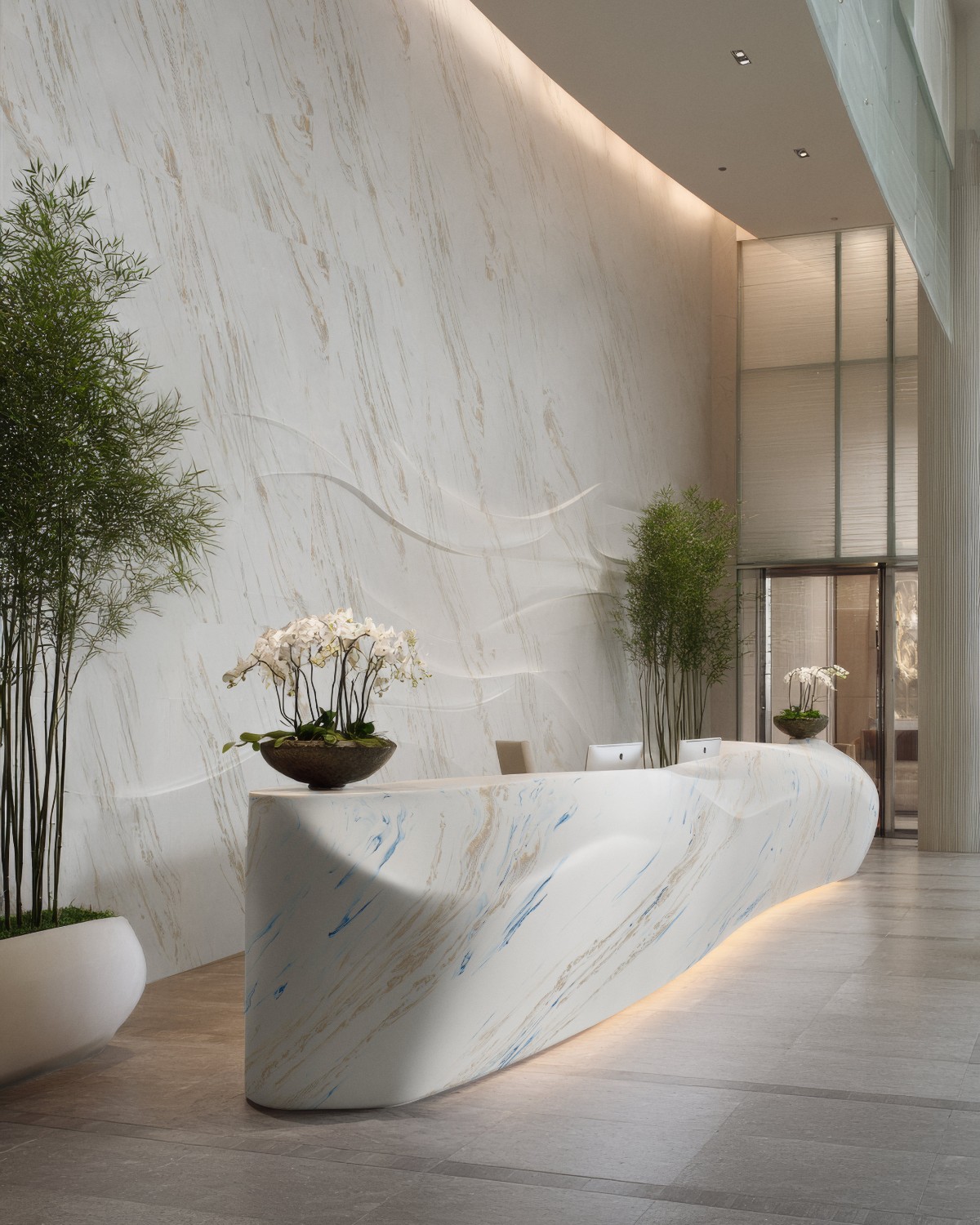Premium lobby με καμπύλο reception desk από Corian® Vasto Laguna σε λευκή βάση με μπλε και θερμές φλεβώσεις